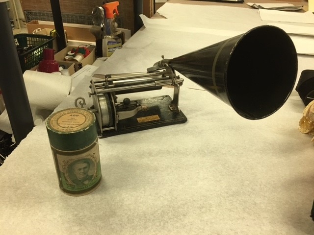 A graphophone, a small machine with rollers and a sound cone.
