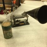 A graphophone, a small machine with rollers and a sound cone.