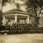 The Park Board Band in one of Milwaukee's parks, posed in front of an octagonal staging pavilion.