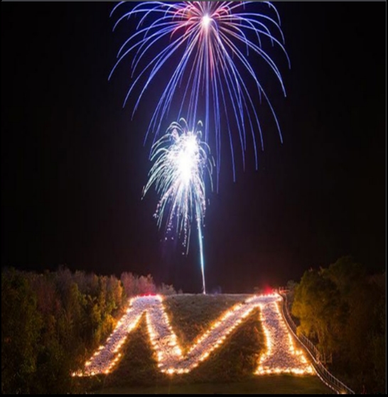 A night-time fireworks display over the 'Platteville M' a giant letter 'M' created with whitewashed fieldstones on the side of a bluff overlooking Platteville.