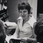 Marge Engelman sits in her office chair talking to students.