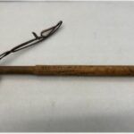 A wooden baton, or night stick with a leather hand strap.