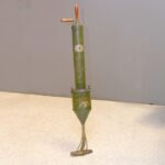 A hand-pump vacuum cleaner, green metal with glass cleaner head and wooden handles