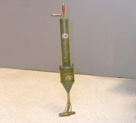 A hand-pump vacuum cleaner, green metal with glass cleaner head and wooden handles