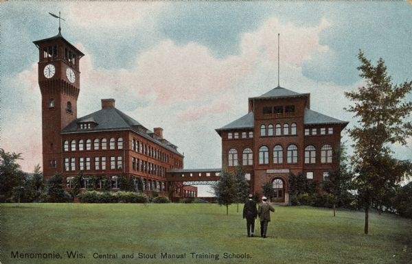 A colorized postcard of two institutional buildings with a bridge spanning between the two. In the foreground, two men walk across a yard toward the buildings. A caption reads, "Menomonie, Wis. Central and Stout Manual Training Schools."