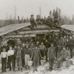 A lumber crew posed in front of one of the log camp buildings.