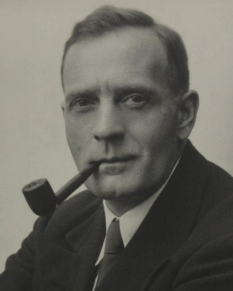 Studio portrait of Edwin Powell Hubble with pipe.