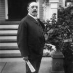 Photo portrait of William Horlick in front of his house holding a rolled newspaper.
