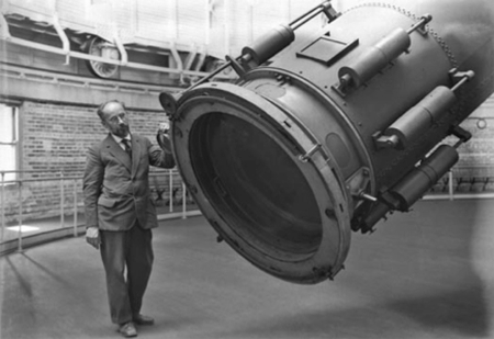 Photograph of a man standing at the base of the forty-inch refractor telescope.