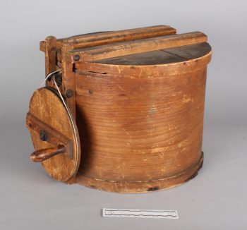 A wooden drum with lid and crank wheel.