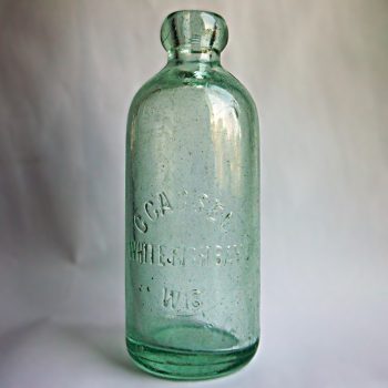 A green glass bottle with molded relief lettering that reads, “C CASSEL WHITE FISH BAY WIS”