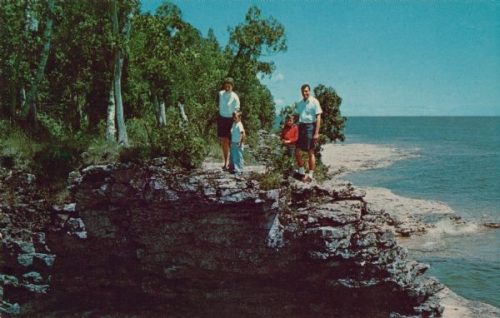 A family stands on the rock ledge at Cave Point overlooking Lake Michigan in the 1960s. Image from Wisconsin Historical Society (#112469).