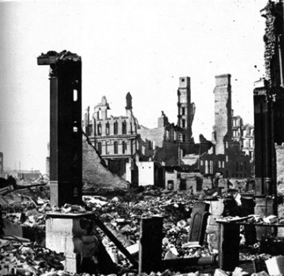 Photograph showing a burned landscape and building ruins.