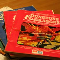 a color photo of several early Dungeons and Dragons rulebooks with dice