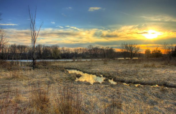 A color photo of Lake Koshkonong at sunset with marsh land in the foreground.
