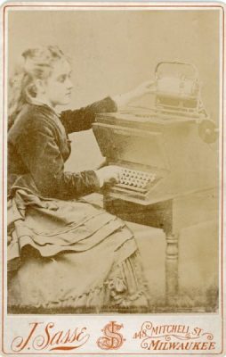 Christopher Sholes's daughter Lillian sitting at a prototype typewriter.