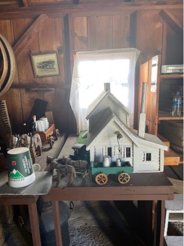 A model cheese factory building with model horse-drawn dairy cart in a workshop-like setting.