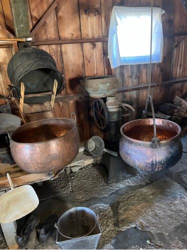 A collections of kettles, scoops, and other cheesemaking supplies.