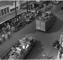 trucks carrying tons of scarp metal through a town during a WWII scrap drive