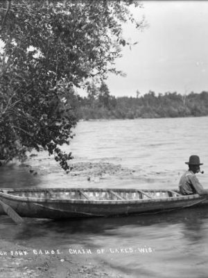Two men and a birch bark canoe beside a lake