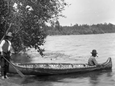 Two men and a birch bark canoe beside a lake