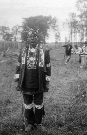 Full-length portrait of Chief Simon Onanguisse Kahquados wearing his beaded military coat.