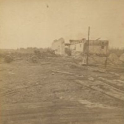 Photograph showing a burned landscape and the hollowed ruins of a building.