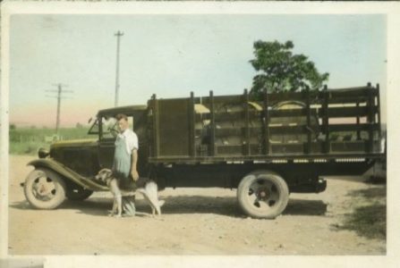 a postcard of a man standing in front of a truck filled with tubs of Swiss cheese